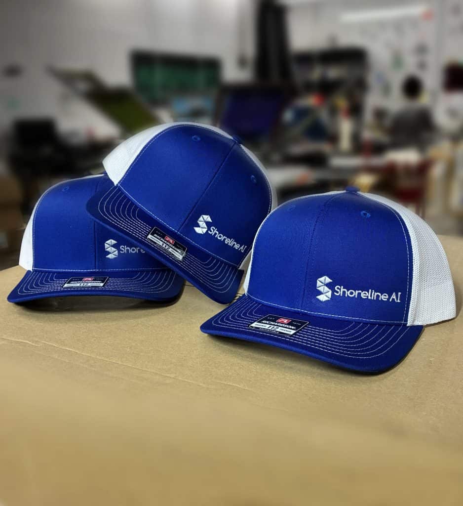 Blue and white Shoreline AI branded Richardson 112 trucker hats embroidery